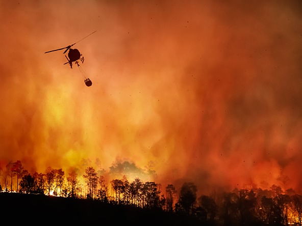 Helicopter flies over forest fire
